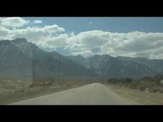 the road is empty and there are mountains in the background with clouds