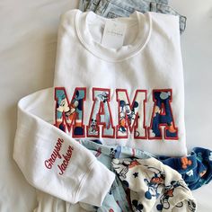 The Embroidered Mama Sweatshirt, adorned with a baby outfit appliqué, offers a heartwarming keepsake idea for mothers, making it an ideal gift for Mother's Day, embodying both sentimentality and style in one mom sweater gift. How to order: 1. Select sweatshirt SIZE and COLOR  2. Select NAME ADD ON 3. In the personalization box please include:  🧵 Text for chest (3-5 letters - MAMA, DAD, DADA, PAPA, GIGI, NANA, etc..) 🧵 Name of child(ren) if needed 🧵 Thread color  🧵 Font Number (thread color i White Tops With Embroidered Graphics For Mother's Day, Embroidered White Tops For Mother's Day, White Embroidered Tops For Mother's Day, Custom Embroidered White Tops For Mother's Day, White Tops With Letter Embroidery For Mother's Day, Family Matching White Sweatshirt With Letter Embroidery, White Family Matching Sweatshirt With Letter Embroidery, White Embroidered Sweatshirt For Gift, White Embroidered Sweatshirt As Gift