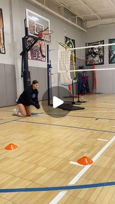 a woman kneeling down on top of a hard wood floor next to a volleyball net