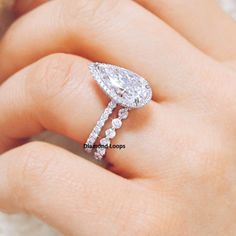 a woman's hand with a diamond ring on top of her finger and an engagement band