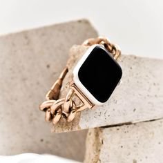 an apple watch sitting on top of a block of concrete with a chain around it