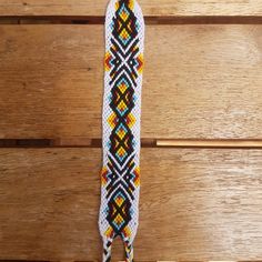 a colorful beaded lanyard hanging on a wooden wall