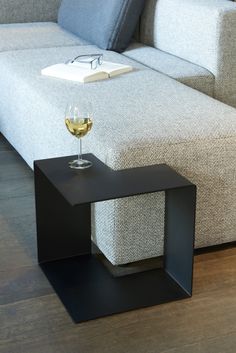 a glass of wine sitting on top of a black table next to a white couch