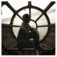 a person sitting in front of a large window with round glass panes on it