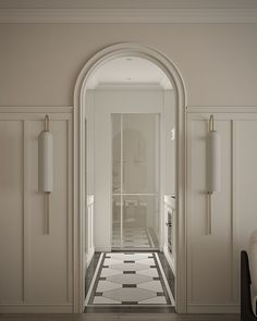 an empty hallway with white walls and black and white checkered flooring, along with two lamps on either side of the doorway