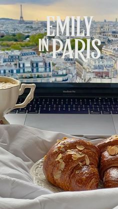 two croissants sitting on a plate in front of a laptop with the eiffel tower in the background