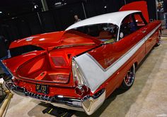 an old red and white car is on display