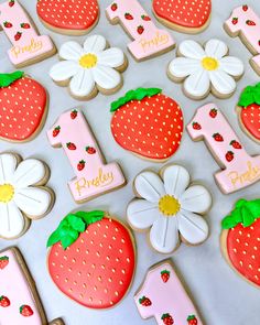 decorated cookies with the number one, strawberrys and daisies are on a table