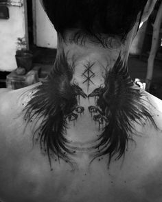 the back of a man's neck with angel wings and cross tattoo on it