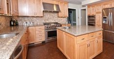 a large kitchen with stainless steel appliances and wooden cabinets, along with granite counter tops