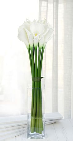 white flowers in a clear vase on a window sill