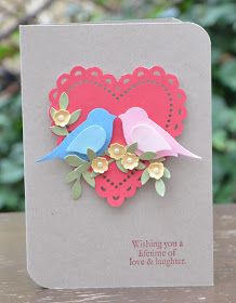 a card with two birds sitting on top of a piece of paper in the shape of a heart