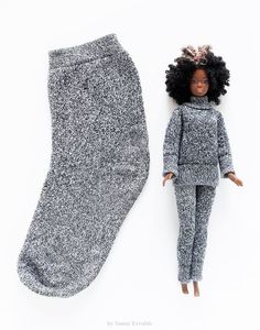 a doll laying next to a pair of socks and leggings on a white background