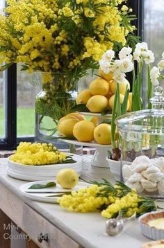 the table is set with lemons, flowers and other foodstuffs on it