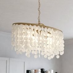 a chandelier hanging from the ceiling in a room with white walls and cabinets