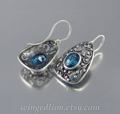 "GERTRUDE earrings are made of sterling silver, еach earring measures 25x18 mm (1\"x0.7\"). Weight - 4gr each.  The earrings are adorned with lavish floral carvings inspired by Medieval decorative motifs and feature sparkling natural London Blue Topaz (oval, 10x8mm, VVS - eye clean, total carat weight about 5ct). Hallmarked with the jeweler's mark and 925 (sterling silver). Designed and crafted by Sergey Zhiboedov. © SZ Jewelry Design A matching pendant is also available. Please let us know if y Blue Sterling Silver Earrings With Intricate Design, Sterling Silver Blue Earrings With Intricate Design, Silver Teardrop Topaz Earrings, Silver Topaz Teardrop Earrings, Ornate Silver Blue Topaz Jewelry, Luxury Silver Topaz Earrings, Antique Diamond, Emerald Engagement Ring, London Blue Topaz