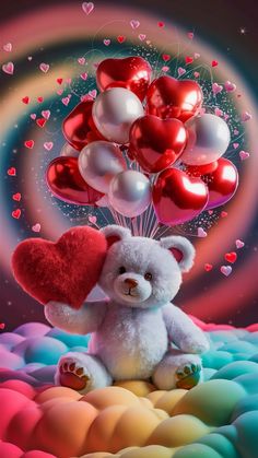 a white teddy bear sitting on top of a rainbow colored surface with balloons in the shape of hearts