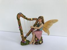 a fairy figurine sitting on top of a harp