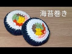 two crocheted sushi coasters sitting on top of a wooden table