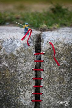 a red string attached to the side of a rock with a toy man on it