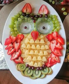 an owl made out of fruit is on a plate with grapes, kiwis and strawberries