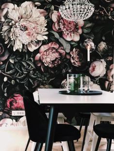 a dining room table with two chairs and a wallpapered floral design behind it