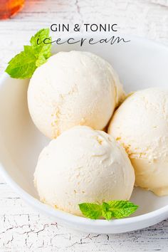 three scoops of ice cream in a white bowl with mint leaves on the side