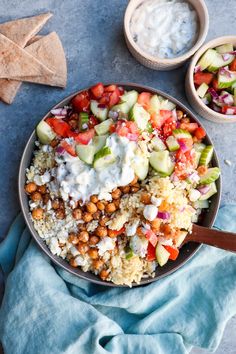 a bowl filled with rice, cucumber, tomatoes and other vegetables next to crackers