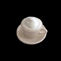 a white cup and saucer on a black background