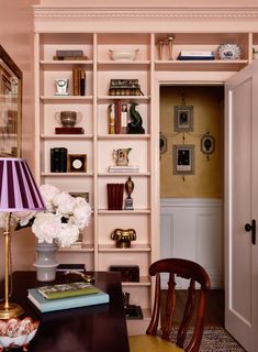 a room with bookshelves, lamps and flowers on the table