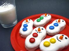 there are four decorated cookies on a red plate next to a glass of milk and a straw