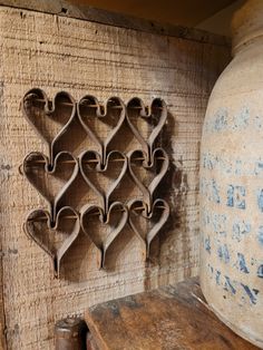 several heart shaped cookie cutters hanging on a wall next to a vase and wooden box