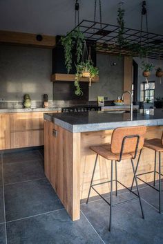 a kitchen with an island and bar stools next to the counter top that has potted plants on it