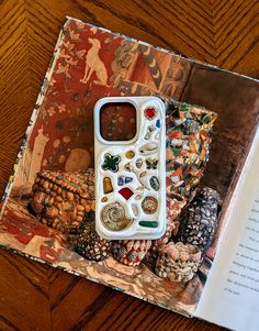 an open book on a wooden table with a cell phone and other items in it