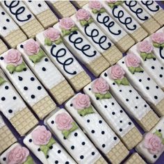 decorated cookies are arranged in the shape of squares and dots with pink roses on them