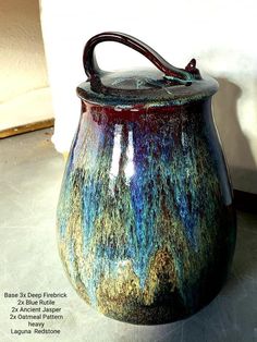 a ceramic pot with handle sitting on top of a table next to a white wall