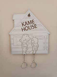 two key chains hanging from the side of a house shaped like a cartoon character with words on it