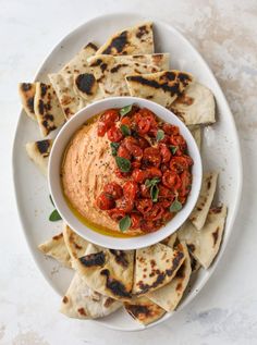 a white plate topped with tortilla chips and a bowl filled with salsa sauce