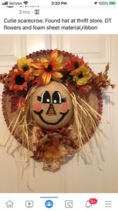 a scarecrow head hanging on a door decorated with fall leaves and dried grass for decoration