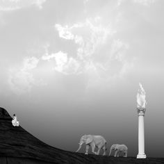 two elephants are standing on top of a hill with an elephant statue in the background