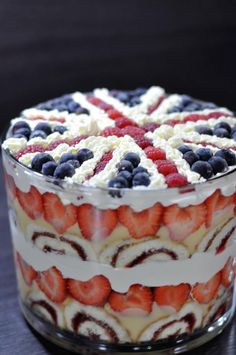 a trifle with strawberries and blueberries in it on a glass dish sitting on a table