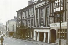 an old black and white photo of people walking down the street in front of buildings