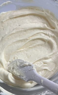 a mixing bowl filled with white batter and a plastic spatula in the bottom right hand corner