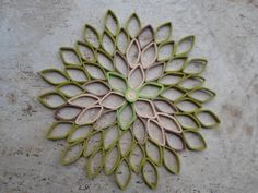 a green and pink flower shaped object sitting on top of a cement floor next to a wall