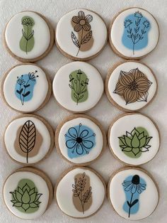 decorated cookies with flowers and leaves are arranged in rows on a white tablecloth background