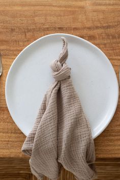 a white plate topped with a napkin on top of a wooden table next to utensils