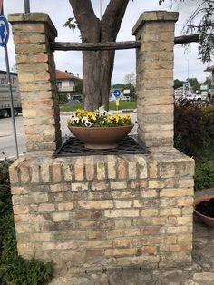 a potted plant sitting on top of a brick fire place next to a tree