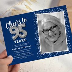 a woman holding up a blue birthday card with the number 95 years printed on it