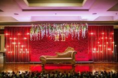 the stage is decorated with red flowers and greenery as well as a gold bench