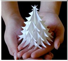 two hands holding a white origami christmas tree